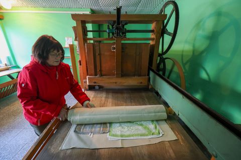 Annerose Illing mangelt die Wäsche ihrer betagten Mutter mit einer historischen Kaltmangel. Foto: Jan Woitas/dpa