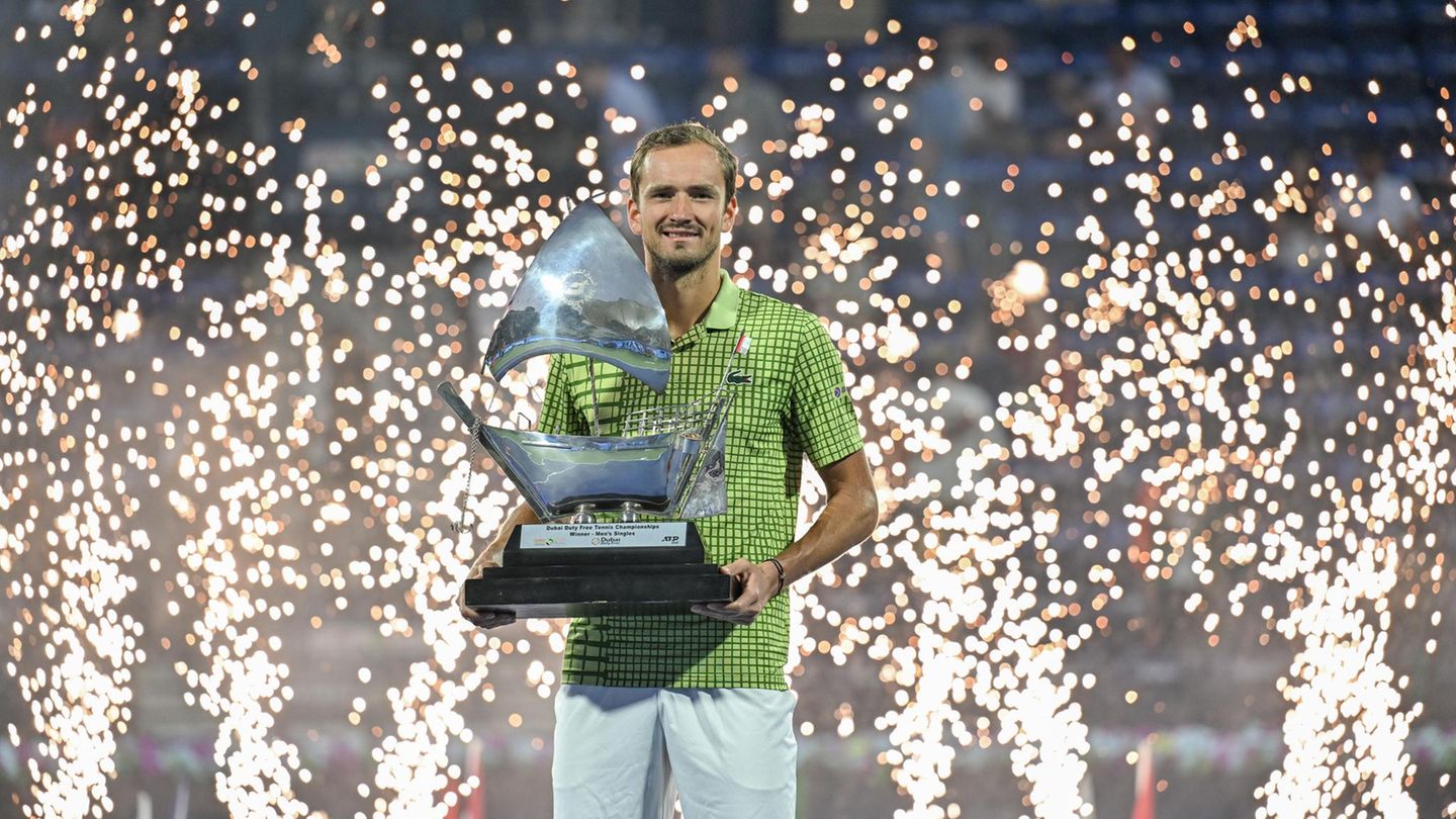 Daniil Medvedev hält eine Trophäe in der Hand, während hinter ihm Funken in die Luft fliegen