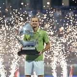Daniil Medvedev hält eine Trophäe in der Hand, während hinter ihm Funken in die Luft fliegen