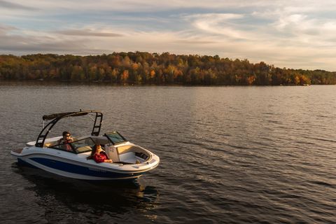 Zwei Personen sind auf einem kleinen Sportboot auf einem See, die Sonne geht gerade außerhalb des Bildes unter.