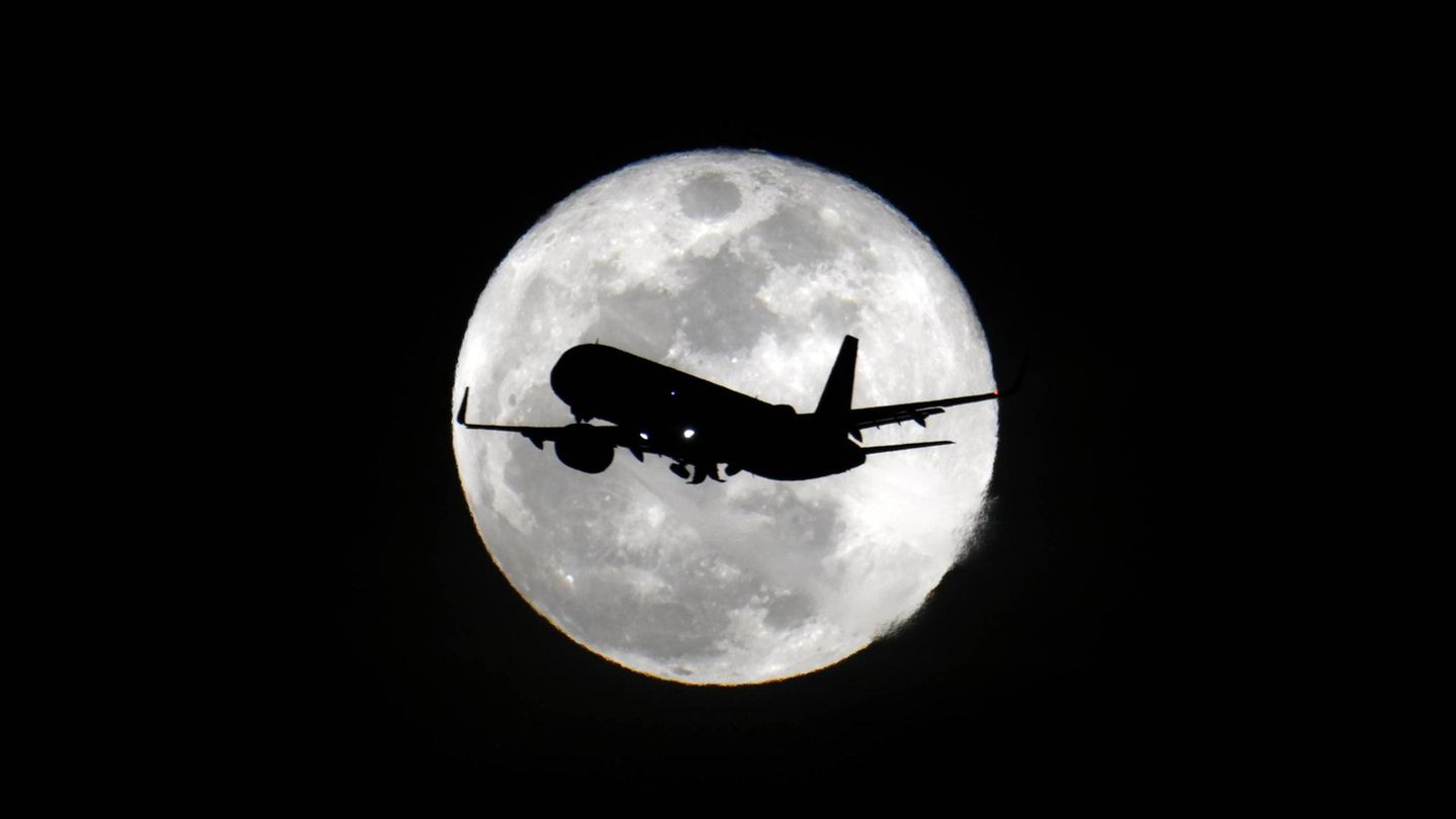 San Francisco, USA. Ein Anblick wie aus einem Film: Ein Passagierflugzeug fliegt vor dem Vollmond am Nachthimmel der Metropolregion im nördlichen Teil des US-Bundesstaates Kalifornien.