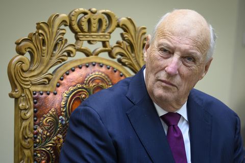 König Harald V. von Norwegen sitzt auf einem Stuhl und blickt in die Kamera