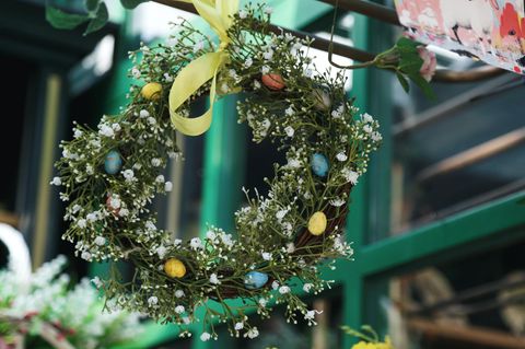 Ein grüner, üppig gebundener Osterkranz mit weißen Blüten und gelber Satin-Schleife