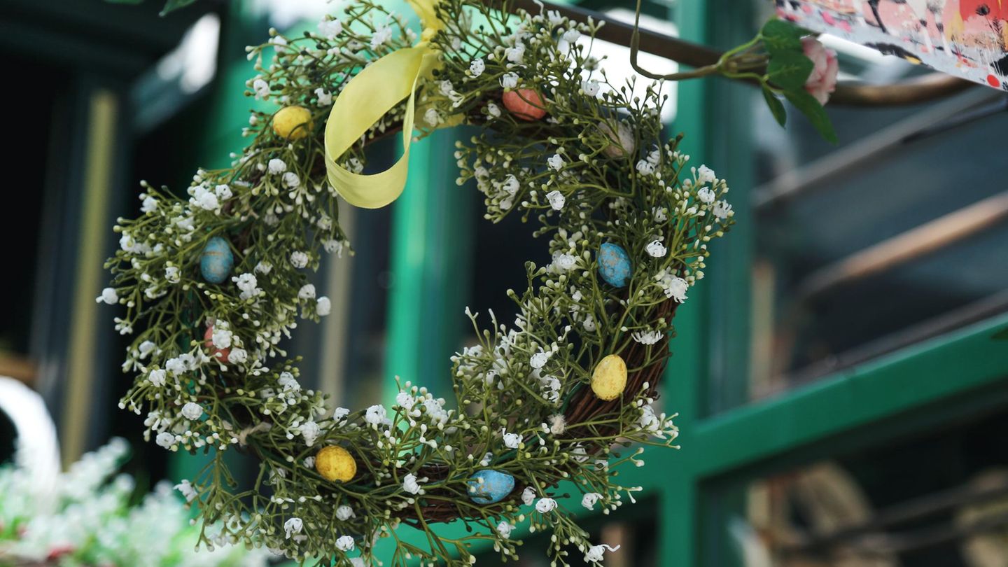 Ein grüner, üppig gebundener Osterkranz mit weißen Blüten und gelber Satin-Schleife