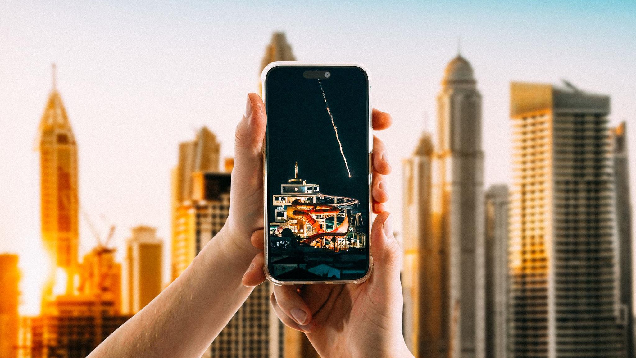 Hände halten ein Smartphone vor der Skyline von Dubai