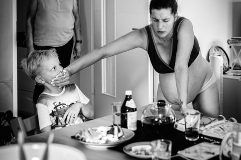 Schwangere Frau in den Wehen hält Kind dem Mund zu