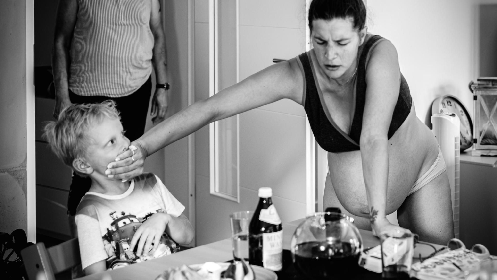 Schwangere Frau in den Wehen hält Kind dem Mund zu