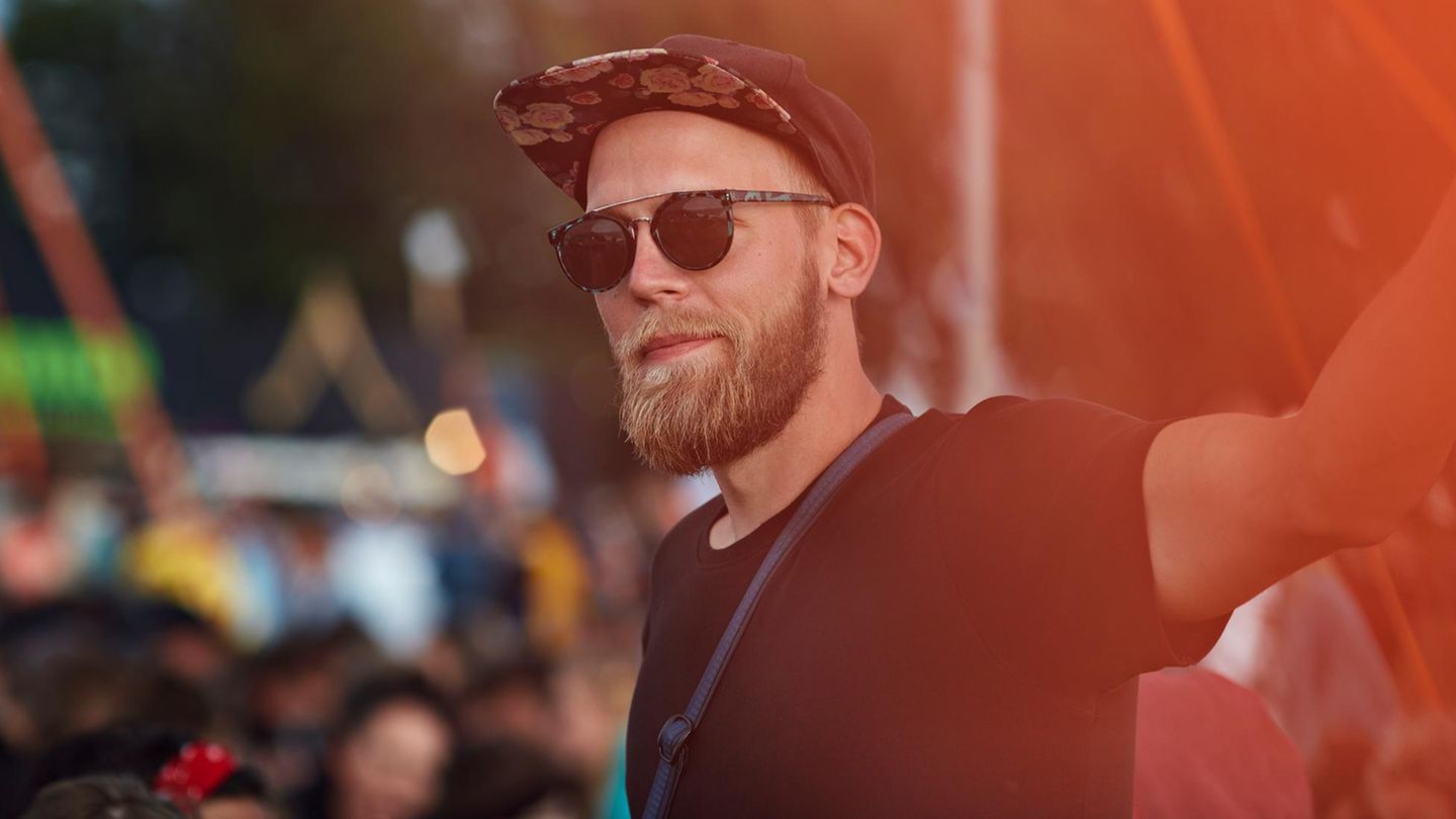 Ein Mann steht ohne Freunde bei einem Festival