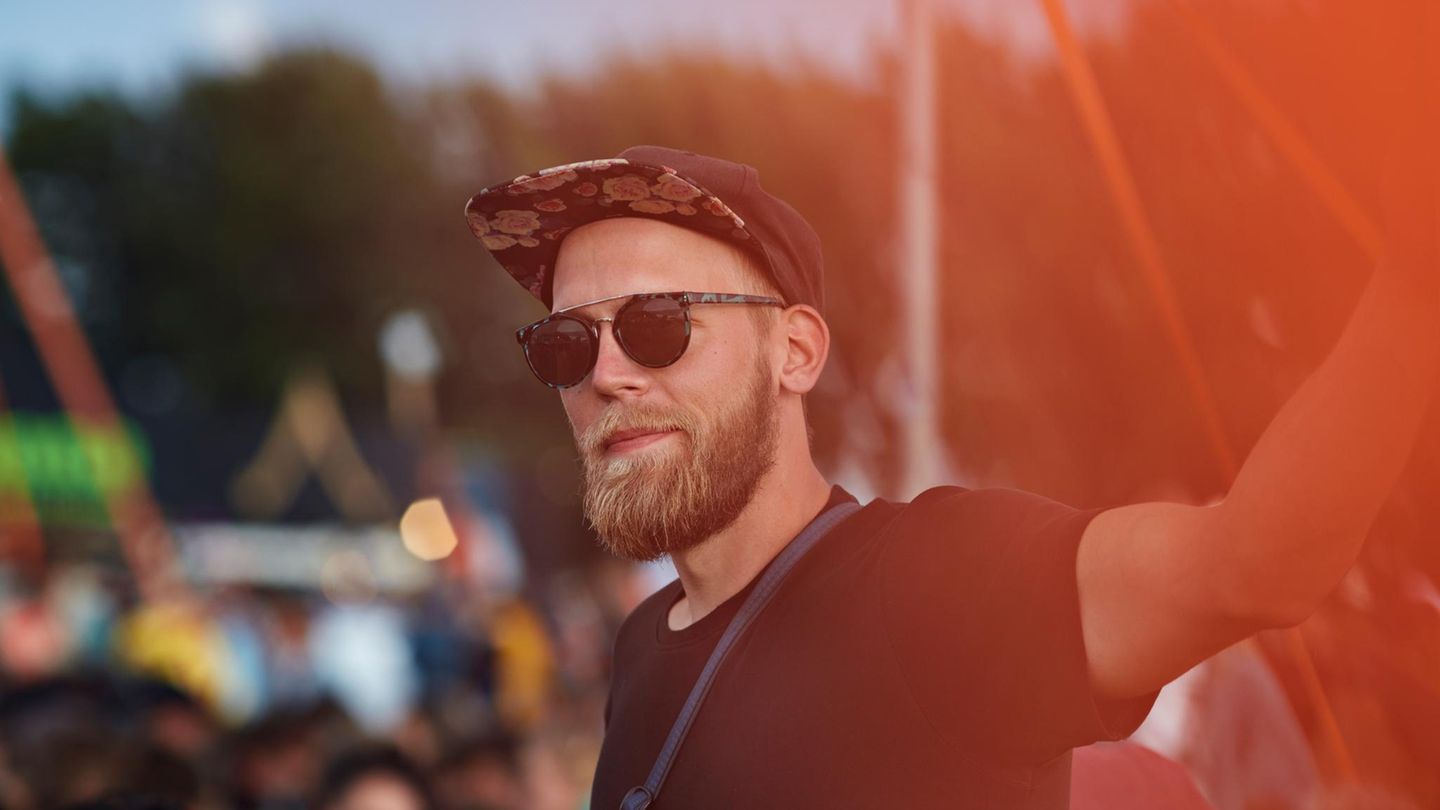 Ein Mann steht ohne Freunde bei einem Festival