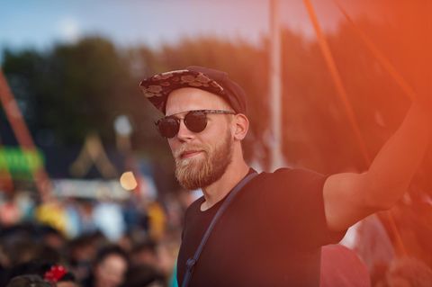 Ein Mann steht ohne Freunde bei einem Festival