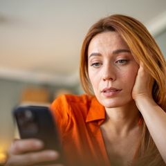 Eine Frau schaut skeptisch ihr iPhone an