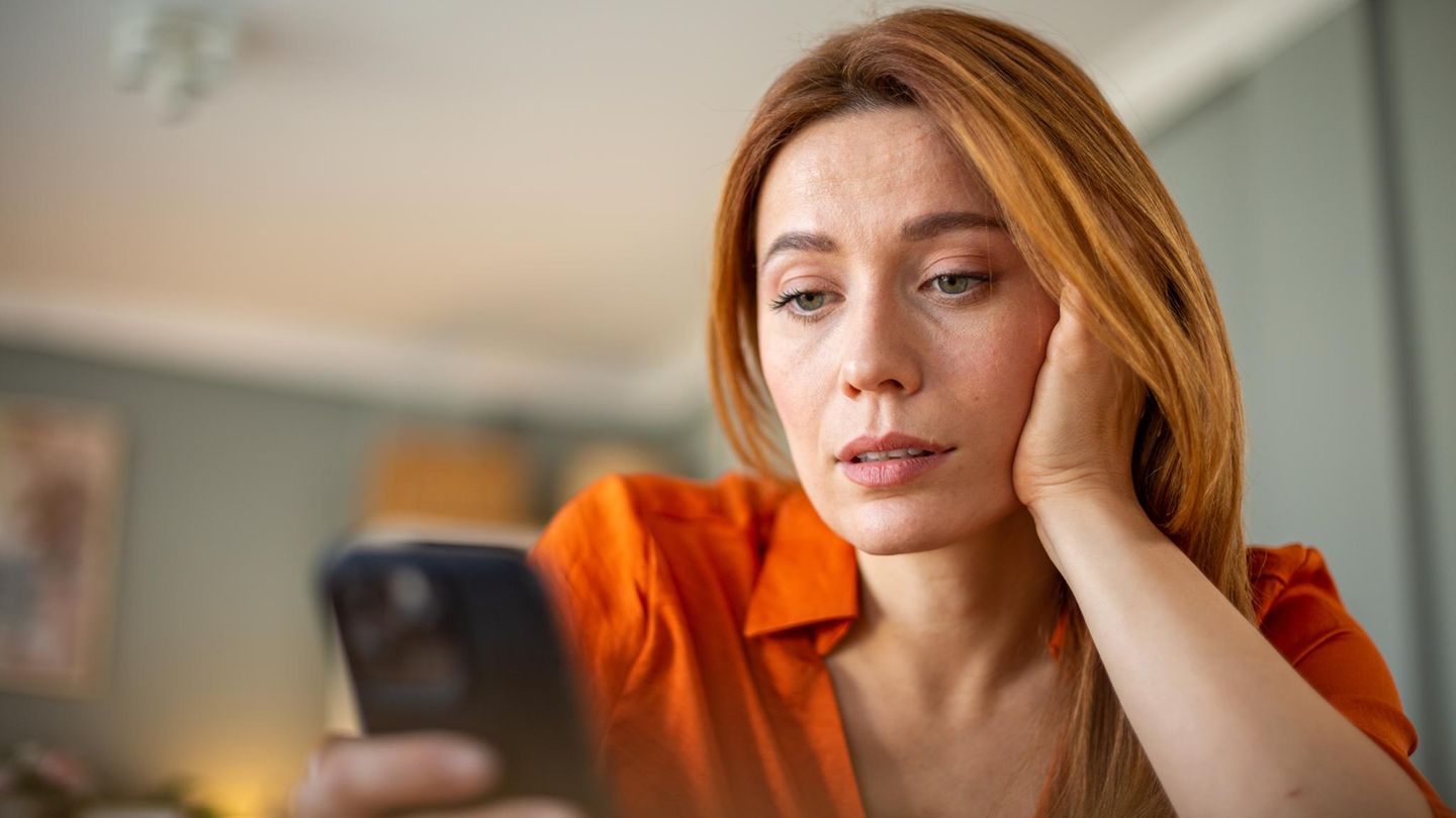 Eine Frau schaut skeptisch ihr iPhone an
