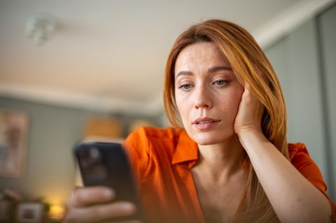 Eine Frau schaut skeptisch ihr iPhone an