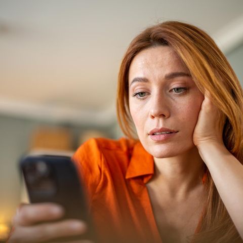 Eine Frau schaut skeptisch ihr iPhone an