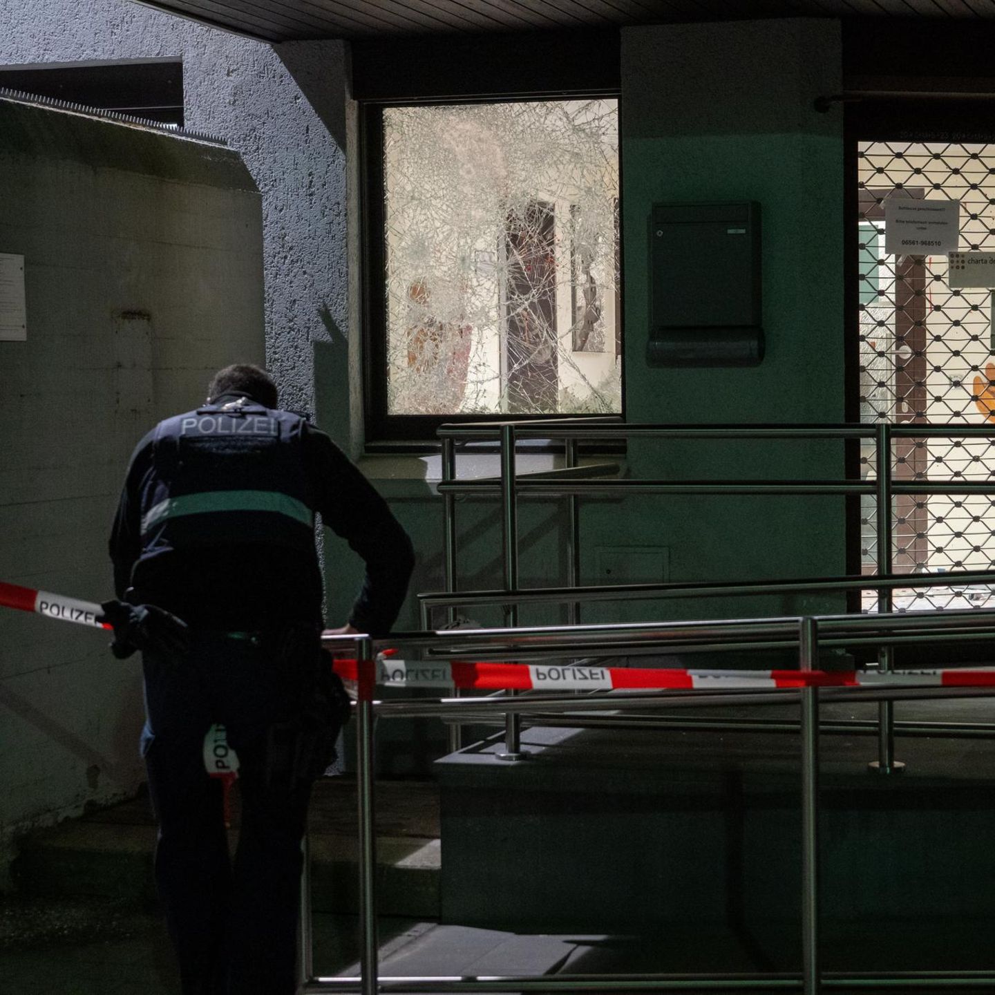 Ein Polizist befestigt ein Absperrband vor der Polizeiinspektion Bitburg