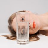 Augen: Frau guckt durch ein Glas Wasser