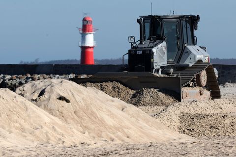Eine Planierraupe räumt derzeit in Warnemünde den Strand auf. Foto: Bernd Wüstneck/dpa