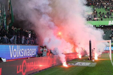 Fans von VfL Wolfsburg zünden Pyrotechnik und beschießen den Platz
