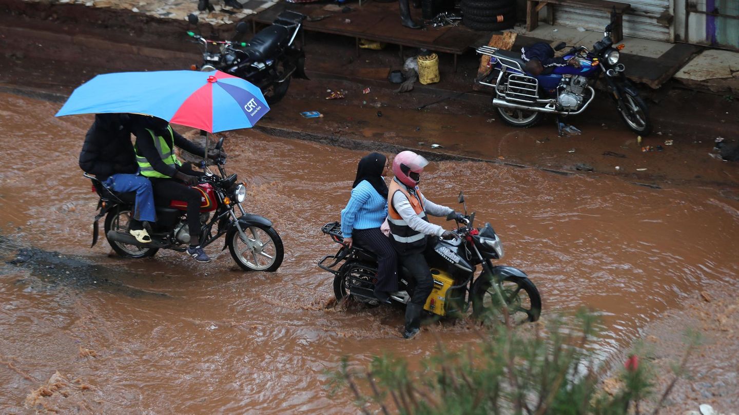 Nairobi, Kenia. Menschen fahren mit Motorrädern auf einer überschwemmten Straße. Die Zahl der Todesopfer der heftigen nächtlichen Regenfälle ist auf 23 gestiegen, während die Rettungsmannschaften weiter nach Überlebenden suchen.