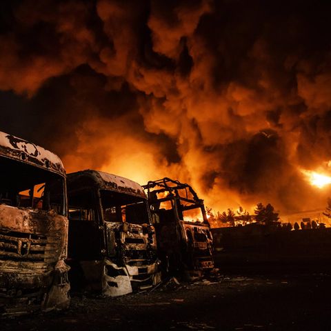 Ausgebrannte Lkw im Vordergrund recht dahinter brennt der Rest des Öldepots in Teheran