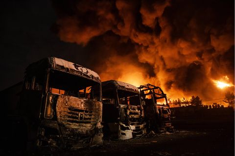 Ausgebrannte Lkw im Vordergrund recht dahinter brennt der Rest des Öldepots in Teheran