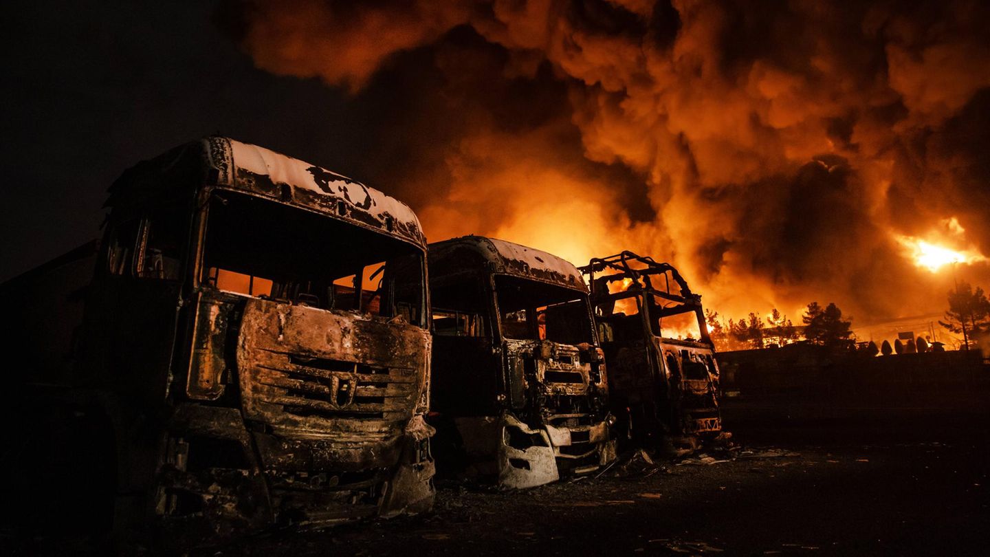 Ausgebrannte Lkw im Vordergrund recht dahinter brennt der Rest des Öldepots in Teheran