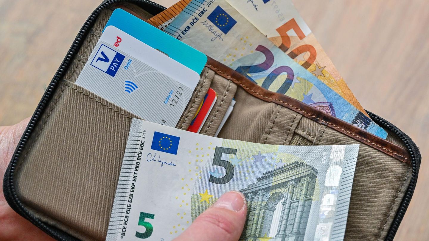 Eine Frau hält in ihrer Hand eine Brieftasche mit Geld und Bankkarten