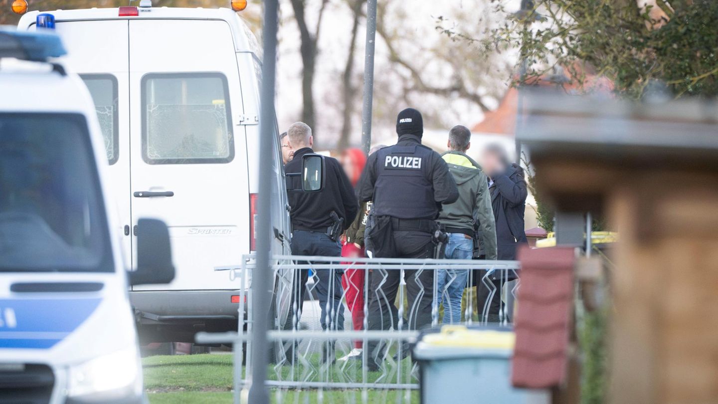 Die Tatverdächtige (Mitte l.) verlässt in Begleitung von Polizeibeamten ihr Wohnhaus (Archiv)