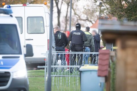 Die Tatverdächtige (Mitte l.) verlässt in Begleitung von Polizeibeamten ihr Wohnhaus (Archiv)