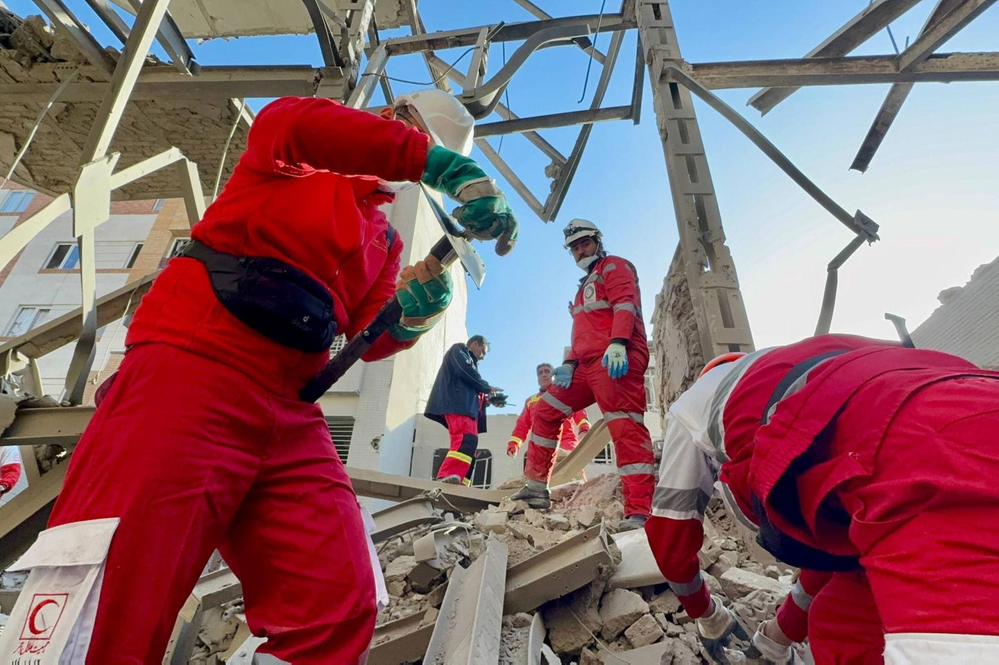 Rettungskräfte des Iranischen Roten Halbmonds (IRCS) bei Bergungsarbeiten eines Gebäudes, das bei einem Luftangriff im Iran beschädigt wurde.