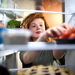 Junge Frau blickt in den Kühlschrank