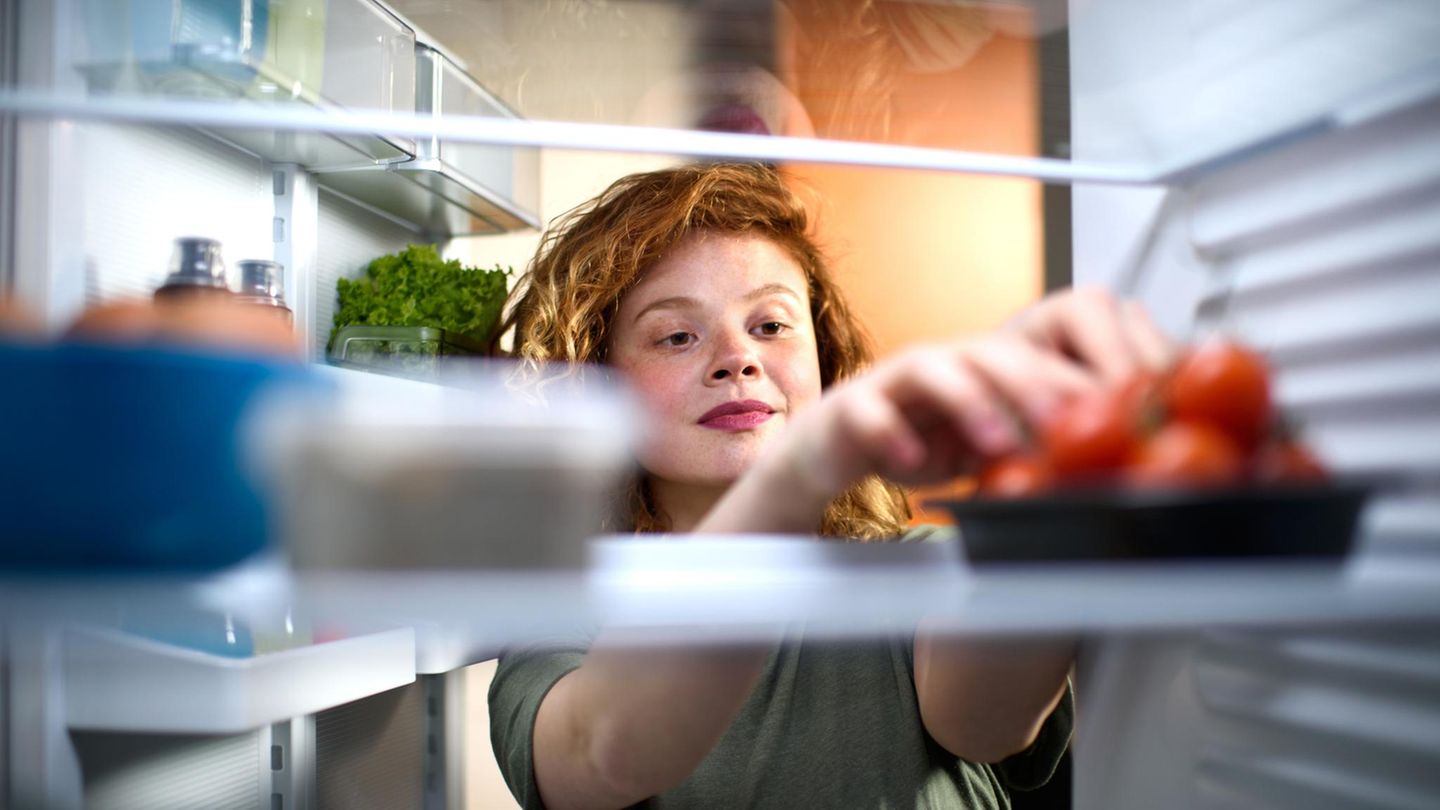 Junge Frau blickt in den Kühlschrank