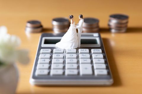 Steuern nach Hochzeit: Brautpaar auf Taschenrechner