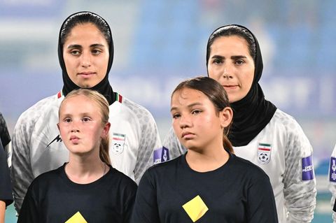 Iranische Fußballerinnen beim Abspielen der Nationalhymne Irans im ersten Gruppenspiel gegen Südkorea, vor Ihnen stehen Schüler.
