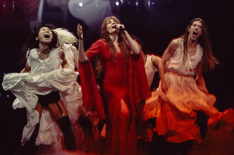 Im roten Kleid tanzt und singt Florence Welch umrahmt von drei weiteren Musikerinnen, die in hellen Kleidern tanzen