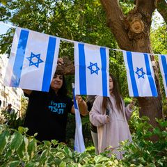 Menschen sitzen versammelt auf einem Platz in Israel