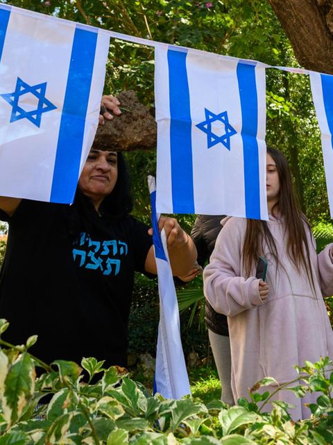 Menschen sitzen versammelt auf einem Platz in Israel