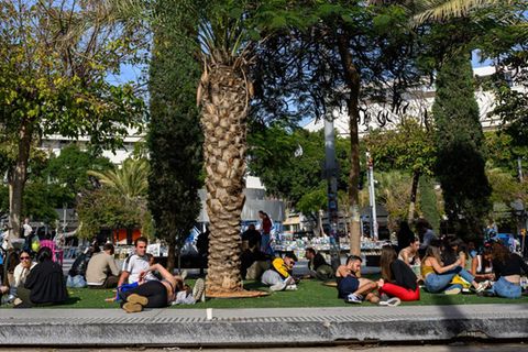 Menschen sitzen versammelt auf einem Platz in Israel