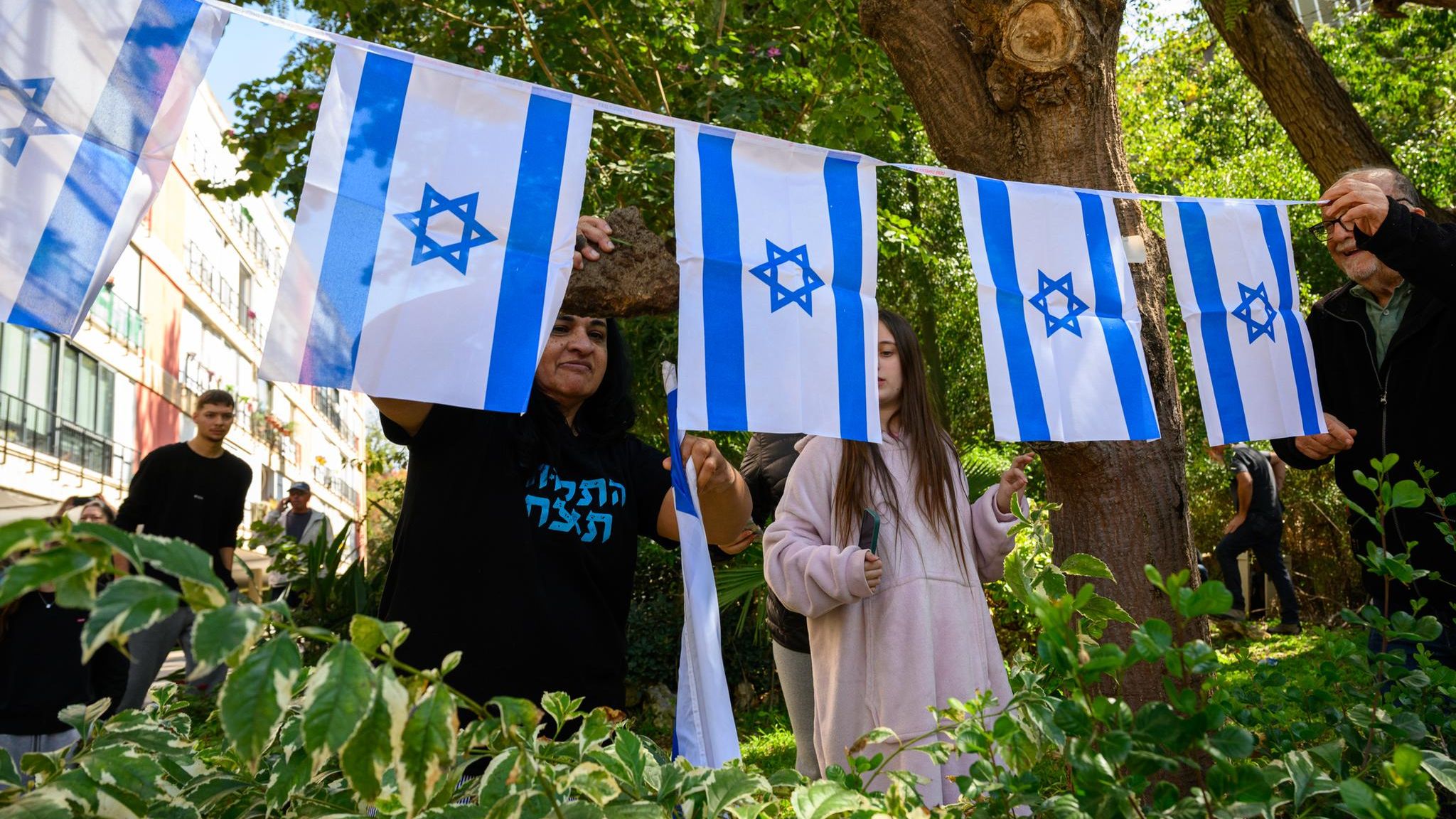 Menschen sitzen versammelt auf einem Platz in Israel