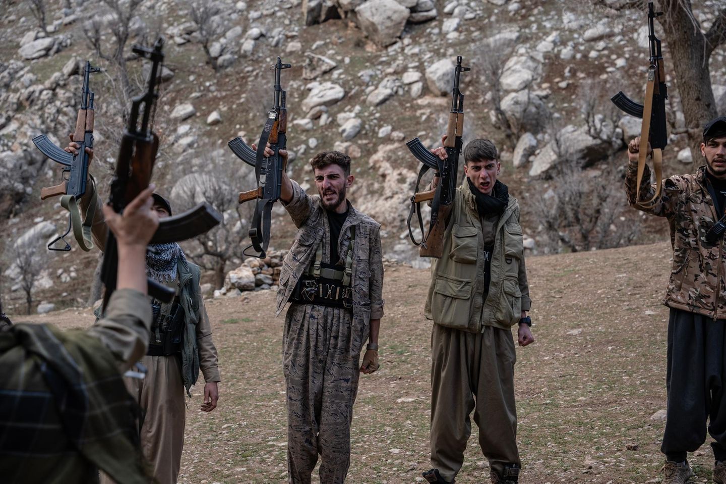 Iranische Dissidentengruppe hält Gewehre in die Luft, die andere Hand zur Faust geballt rufen sie etwas gemeinsam.