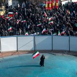 Iranische Frau steht alleine in der Mitte mit einer Iranflagge und demonstriert. Um sie herum eine Absperrung mit weiteren.
