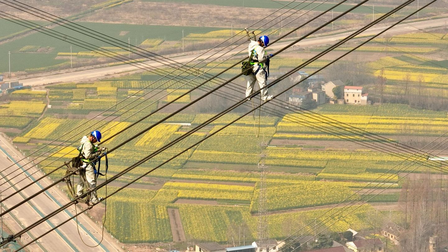 Tongling, China. Höhenarbeiter balancieren bei der Überprüfung einer Hochspannungsleitung am Jangtse-Fluss im Kreis Zongyang in der ostchinesischen Provinz Anhui.
