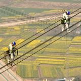 Tongling, China. Höhenarbeiter balancieren bei der Überprüfung einer Hochspannungsleitung am Jangtse-Fluss im Kreis Zongyang in der ostchinesischen Provinz Anhui.