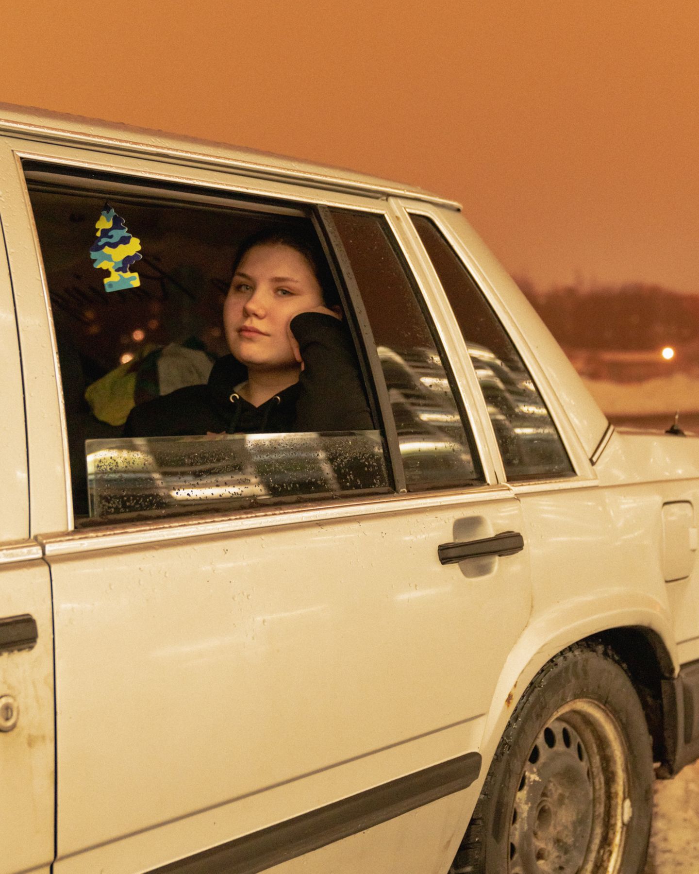 Junge Frau sitzt im Auto und schaut aus dem Fenster.