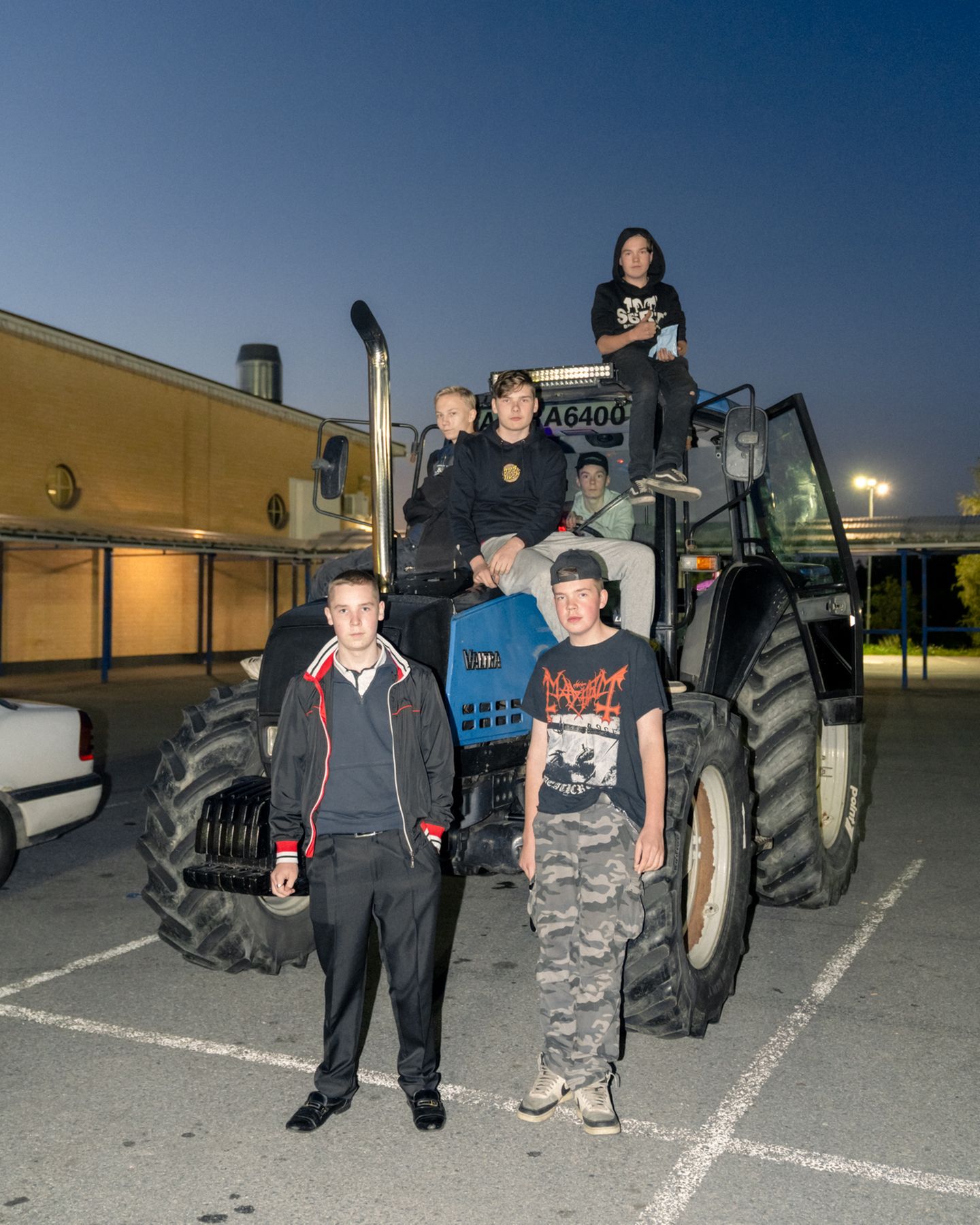 Sechs junge Teenager posieren auf einem Traktor in der Abenddämmerung