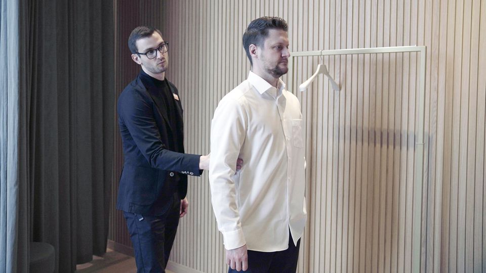 Roy Sorg und der Tester überprüfen bei der Anprobe den Schnitt des Hemds