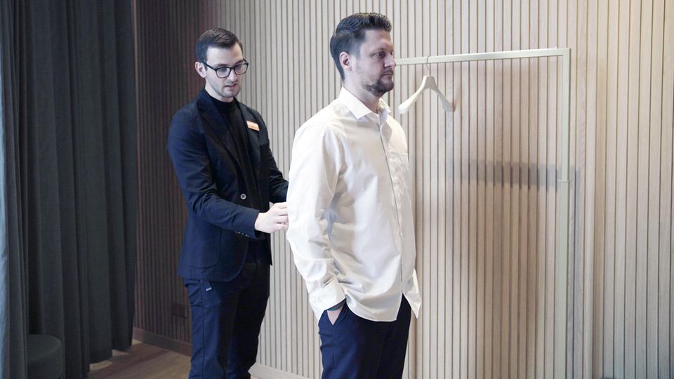 Roy Sorg und der Tester überprüfen bei der Anprobe den Schnitt des Hemds