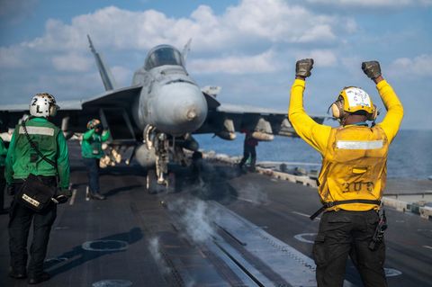 Ein Soldat der US-Marine gibt einer F/A-18E Super Hornet das Signal zum Start vom Flugzeugträgers USS Abraham Lincoln