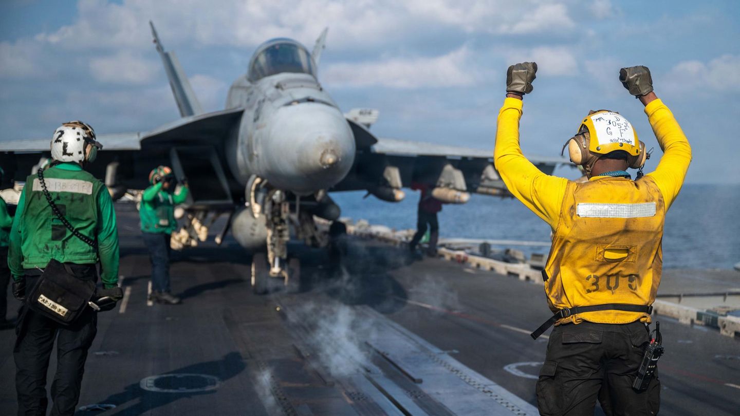 Ein Soldat der US-Marine gibt einer F/A-18E Super Hornet das Signal zum Start vom Flugzeugträgers USS Abraham Lincoln