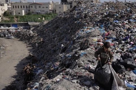 Ein Junge sammelt Müll in Gaza.